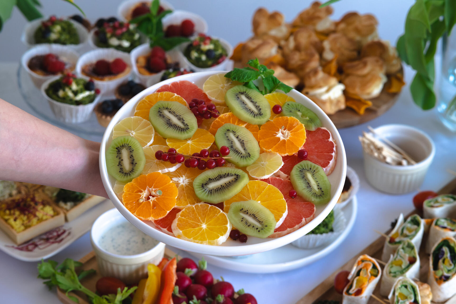 Biały talerz z kolorowymi owocami - kiwi, pomarańcza, żurawina, grejpfrut.