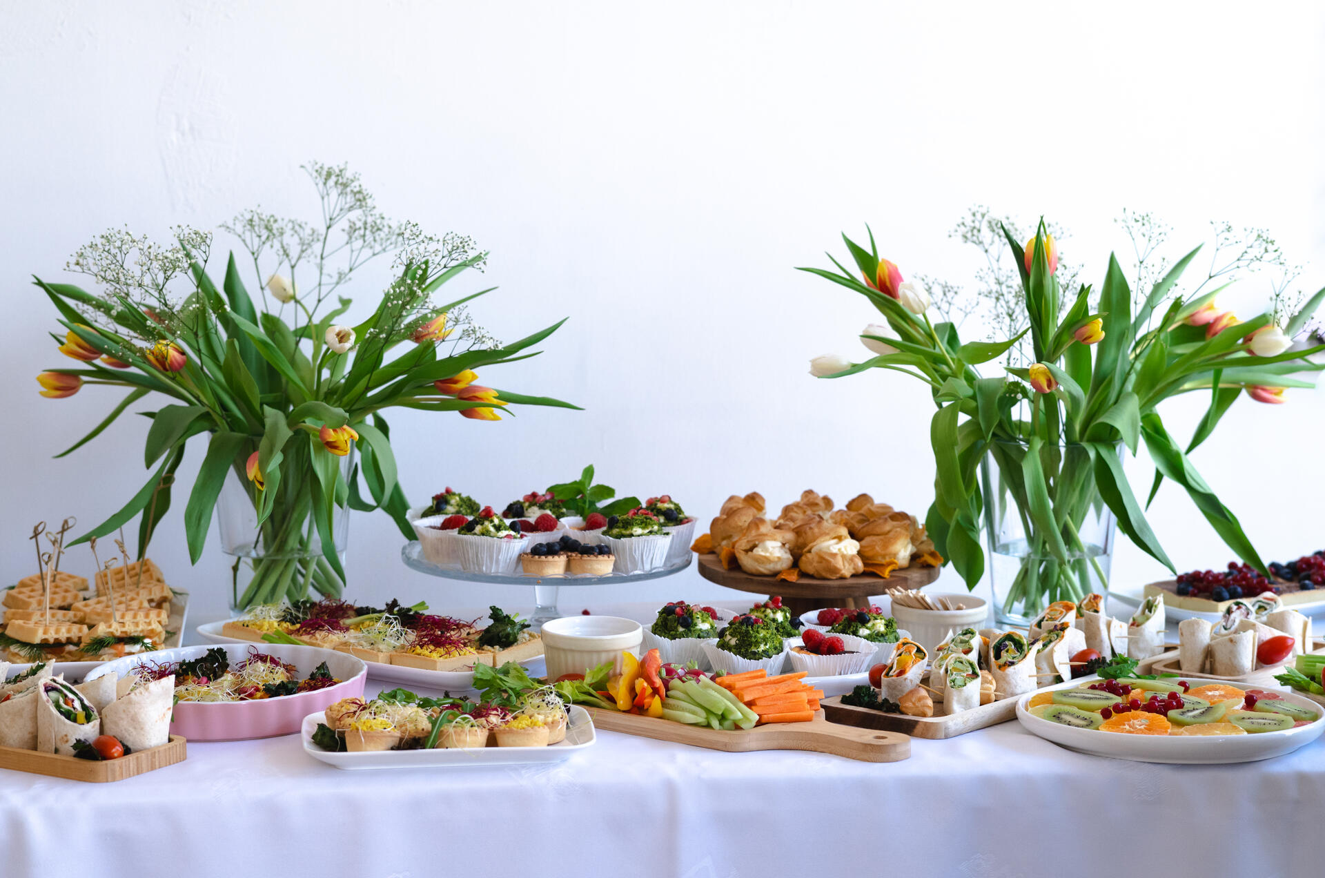 Stół z daniami cateringowymi - zimna płyta, wiosenne kwiaty w wazonie